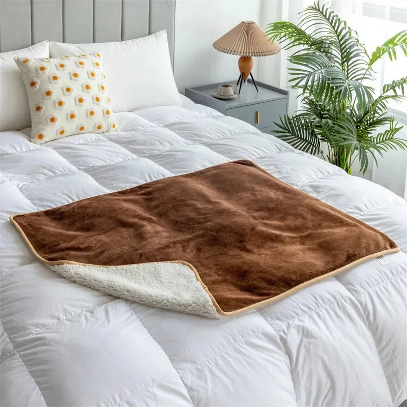 The Everywhere Blanket in Mocha with its sherpa-style reverse on a white bed.