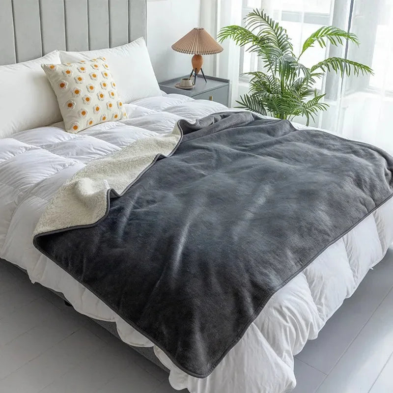 The Everywhere Blanket in Gray draped across a white bed.
