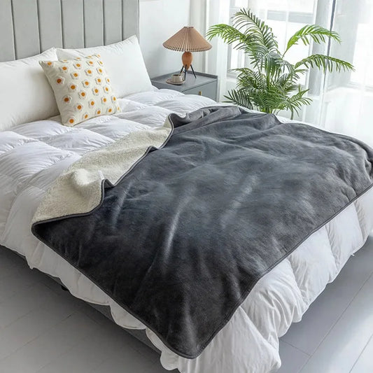 The Everywhere Blanket in Gray draped across a white bed.