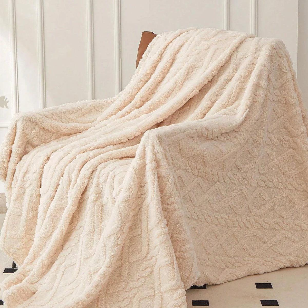Cream Featherweight Throw folded over an armchair.